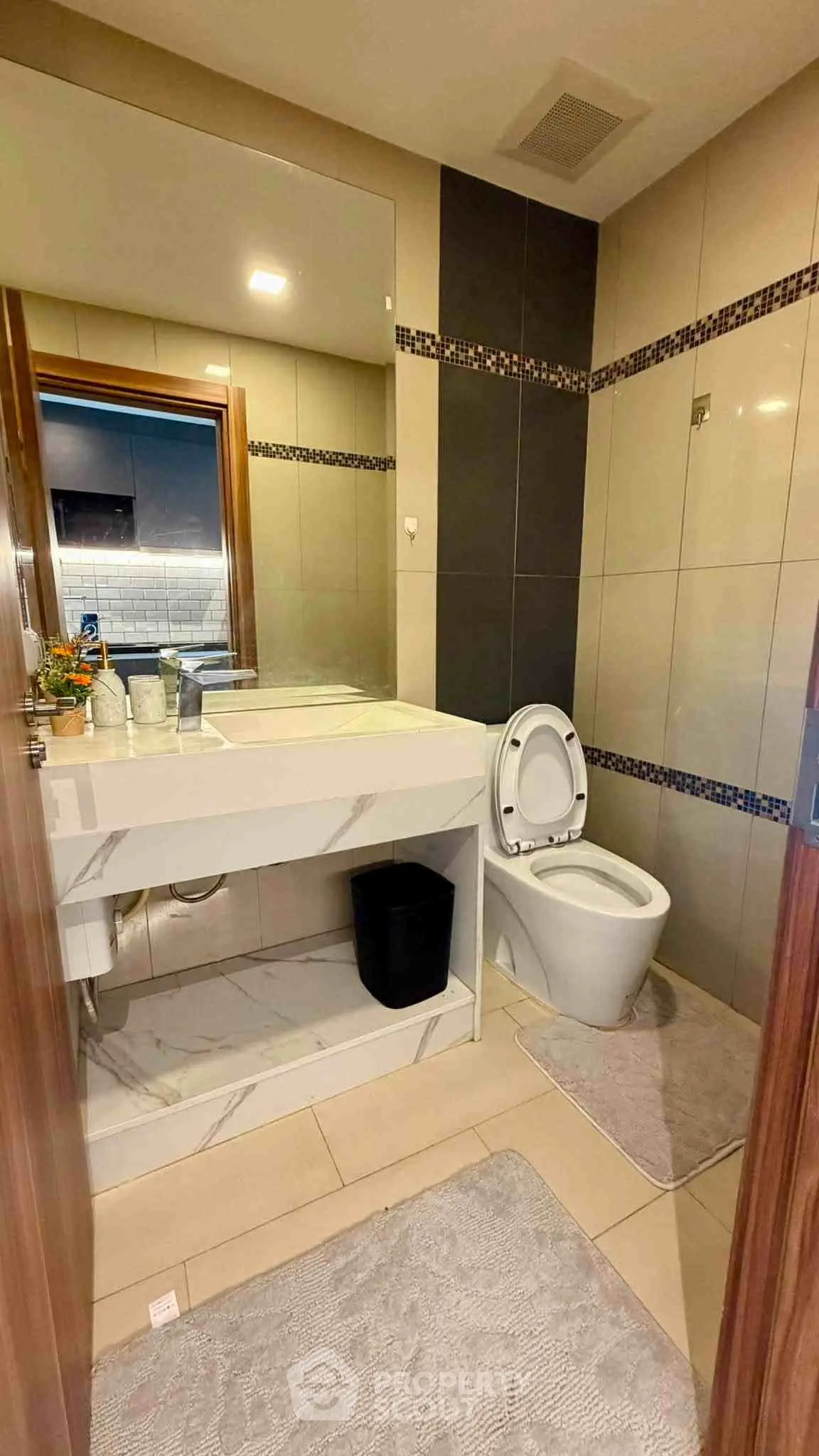 Modern bathroom with sleek design and elegant fixtures, featuring a large mirror and stylish tile work.