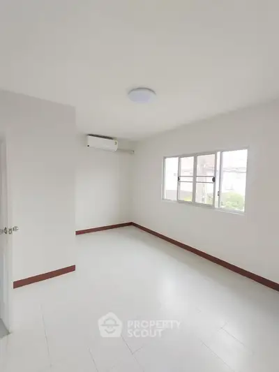Bright and airy empty room with large window and air conditioning unit.