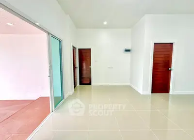 Spacious modern interior with sleek tile flooring and wooden doors, perfect for versatile living arrangements.