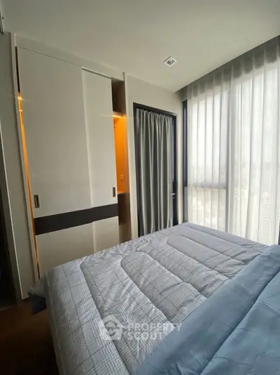 Modern bedroom with large windows and built-in closet in a high-rise apartment.