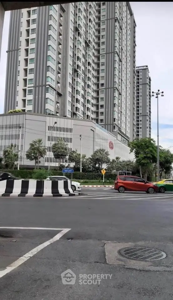 Modern high-rise building exterior with street view and parked cars.