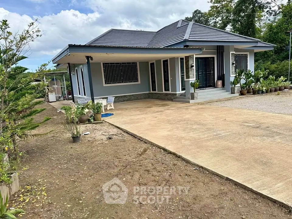 Charming single-story home with modern design, spacious driveway, and lush greenery, perfect for serene living.