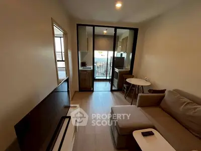Cozy modern living room with open kitchen and balcony view.