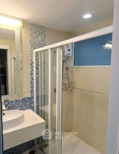 Modern bathroom with glass shower enclosure and stylish sink in contemporary apartment.