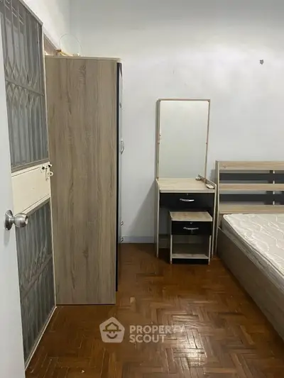 Cozy bedroom with wooden flooring, wardrobe, and a mirror desk, perfect for comfortable living.