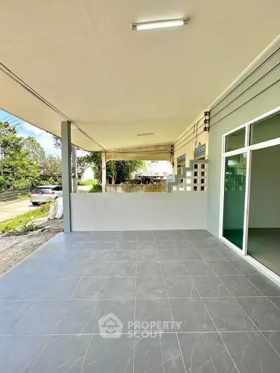 Spacious covered patio with tiled flooring and garden view, perfect for outdoor relaxation.