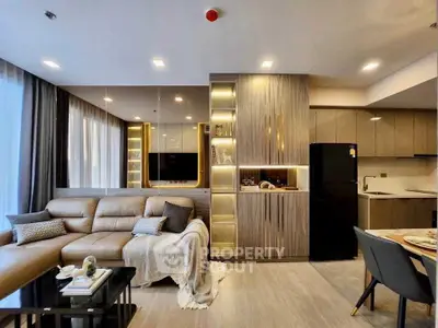 Modern living room with sleek design and open kitchen layout, featuring elegant lighting and contemporary furniture.