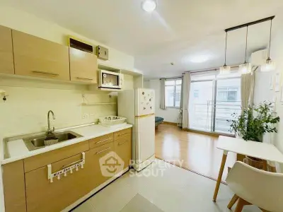 Modern open-layout kitchen with dining area and bright living space, featuring stylish lighting and large windows.