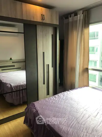 Cozy bedroom with modern wardrobe and large window offering natural light