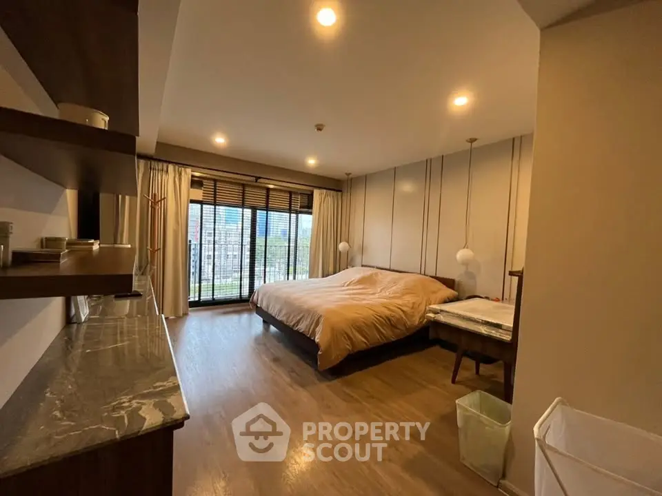 Spacious bedroom with large windows and modern decor in a luxurious apartment.