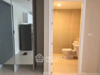 Modern apartment interior with bathroom and kitchen area, featuring sleek design and neutral tones.