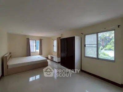 Spacious bedroom with large windows and modern furniture in a bright apartment.