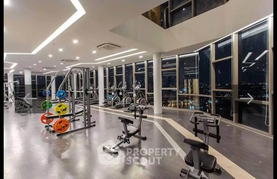 Luxurious gym with panoramic city views and modern fitness equipment.