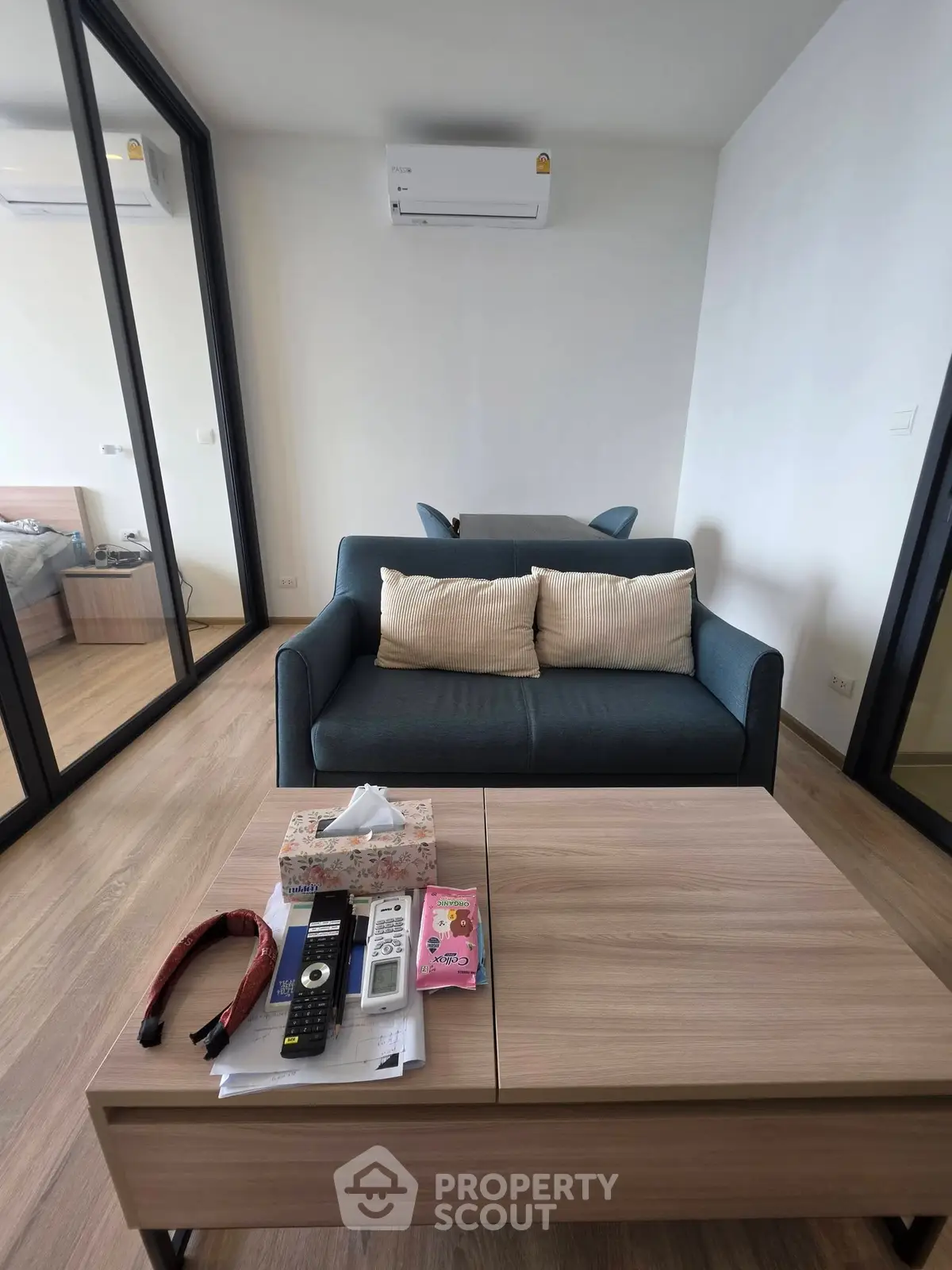 Modern living room with sleek furniture and mirrored closet doors, showcasing a cozy and stylish interior design.