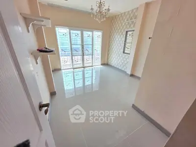 Spacious room with elegant chandelier and large windows offering ample natural light.