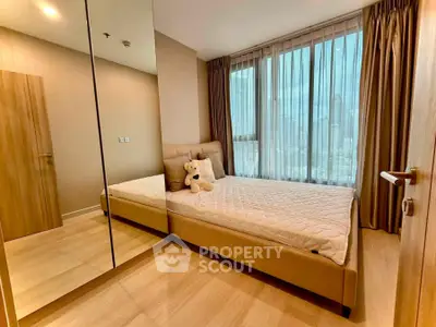Modern bedroom with large windows and mirrored wardrobe in a high-rise apartment.