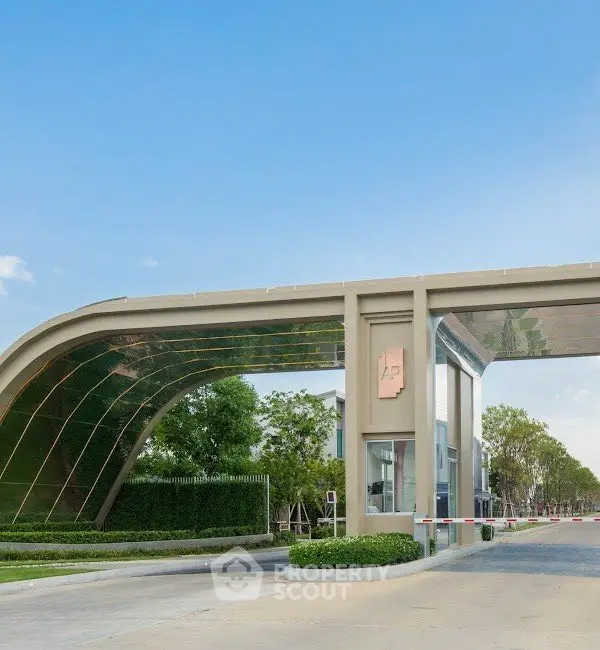 Modern gated entrance of luxury residential community with lush greenery and sleek architectural design.