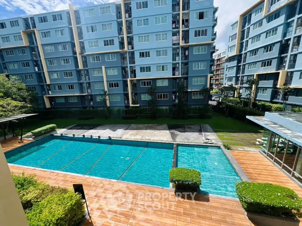 Modern apartment complex with a spacious outdoor swimming pool and lush greenery.