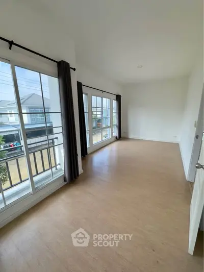 Spacious empty room with large windows and wooden flooring, perfect for customization.