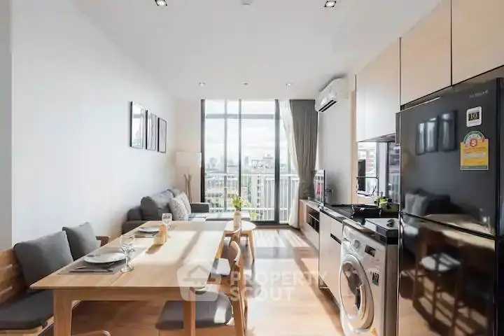 Modern open-plan living room with dining area and balcony view in a stylish apartment.