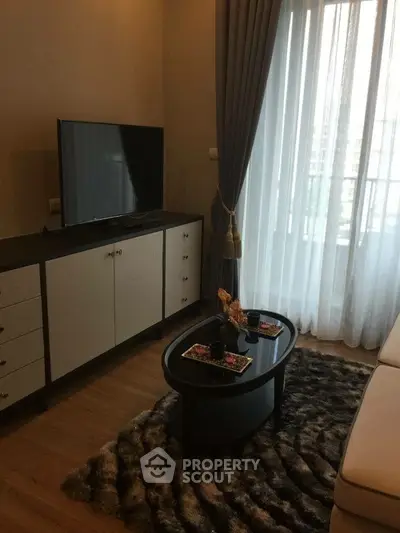 Cozy living room with modern decor and large window offering natural light.