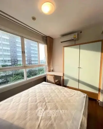 Bright bedroom with large window and modern furniture in urban apartment