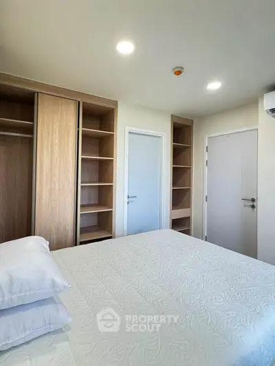 Spacious bedroom with built-in wooden closets and modern lighting, perfect for a cozy retreat.