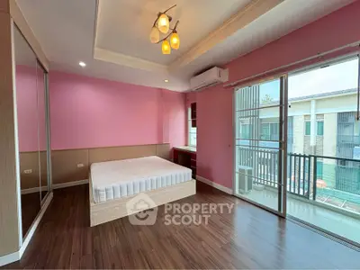 Spacious bedroom with pink walls, large windows, and balcony access in modern apartment.