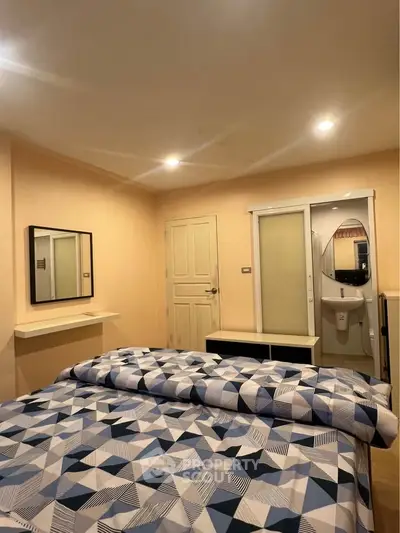 Cozy bedroom with modern decor and geometric bedding in a well-lit space.