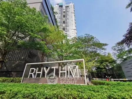 Modern high-rise building with lush greenery at Rhythm condominium entrance.
