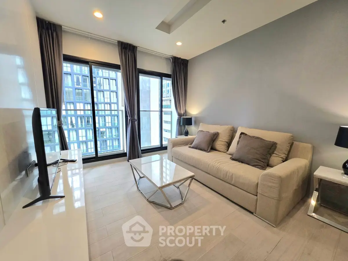 Modern living room with large windows and stylish furniture in a high-rise apartment.