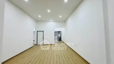 Spacious empty room with wooden flooring and bright lighting, ideal for customization.