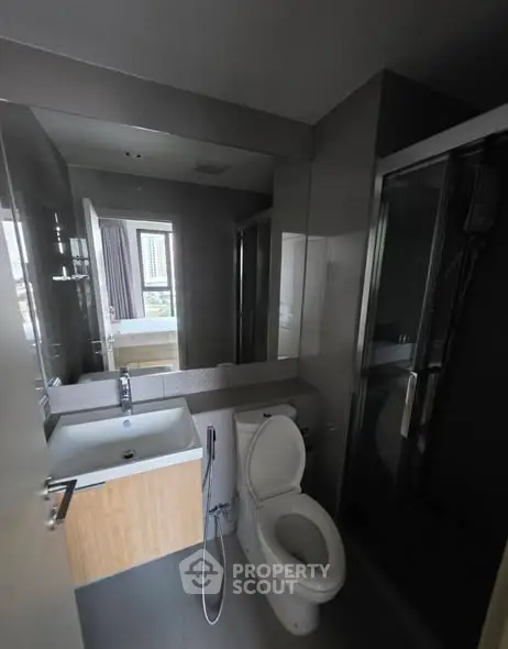 Modern bathroom with sleek fixtures and a large mirror, featuring a shower and toilet in a compact layout.
