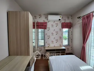 Charming bedroom with floral wallpaper and natural light, featuring a cozy bed and modern furniture.