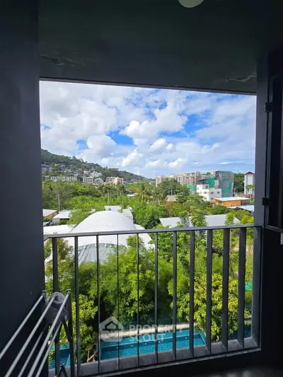 Stunning balcony view overlooking lush greenery and cityscape with blue skies.