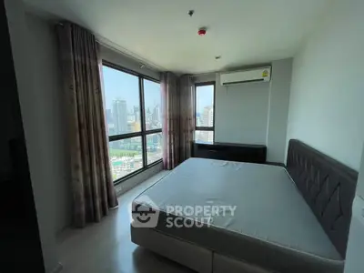 Spacious bedroom with large windows offering stunning city views, featuring a comfortable bed and modern decor.