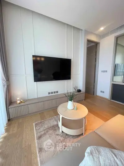 Modern living room with sleek TV setup and stylish decor, featuring light wood flooring and elegant paneling.