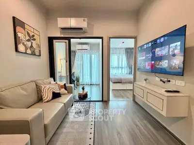 Modern living room with sleek decor and wall-mounted TV, leading to a cozy bedroom.