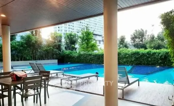 Luxurious poolside area with modern seating and lush greenery in a high-end residential complex.