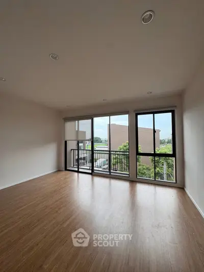 Spacious living room with large windows and balcony access, offering natural light and urban views.