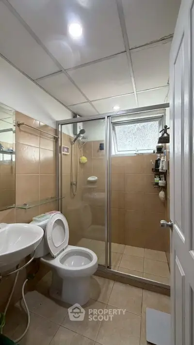 Modern bathroom with glass shower enclosure and tiled walls in a cozy apartment.
