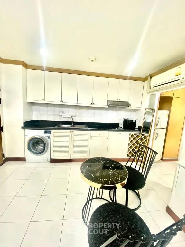 Modern kitchen with sleek cabinets, washing machine, and stylish dining set.