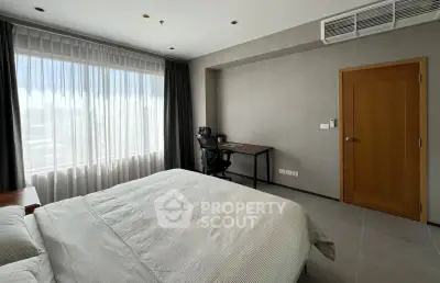 Spacious bedroom with large window and study area, perfect for modern living.