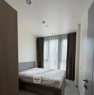 Modern bedroom with large window and stylish curtains in a contemporary apartment.