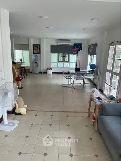 Spacious living room with tiled floor, dining area, and indoor basketball hoop, perfect for family activities.