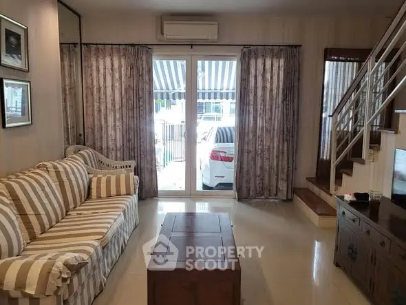Cozy living room with striped sofa and modern staircase, perfect for relaxation.