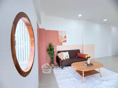 Stylish modern living room with unique circular window and cozy decor.