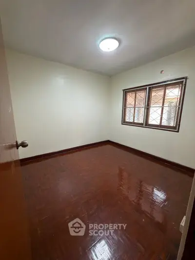 Spacious empty bedroom with polished wooden floors and natural light.
