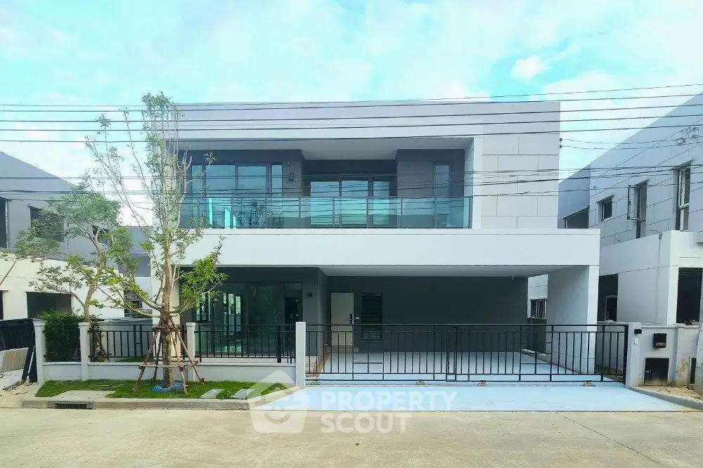 Modern two-story house with sleek design and spacious driveway in a suburban neighborhood.