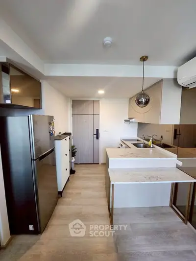 Modern kitchen with sleek design, featuring stainless steel fridge and stylish pendant lighting.